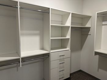 A walk in closet with shelves and drawers and